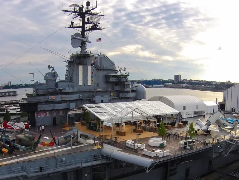 The Center of the Flight Deck is tented with a clear tent for a summer event with lounge furniture and decor