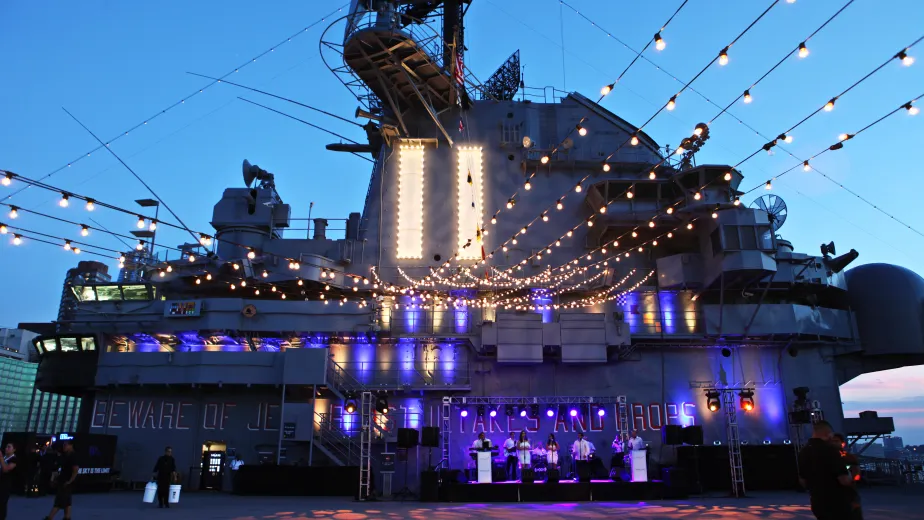 String lighting and uplighting is set with the band on stage with the Flight Deck Island as the backdrop